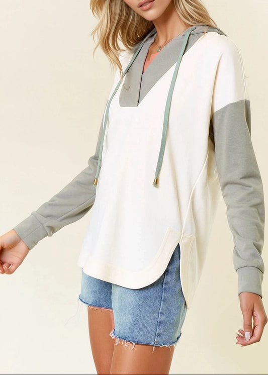 Woman wearing a Sage and Ivory Color Block Hoodie with curved hem and kangaroo pocket. 