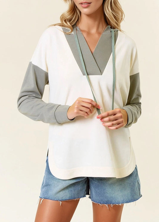 Woman wearing a Sage and Ivory Color Block Hoodie with curved hem and kangaroo pocket. 