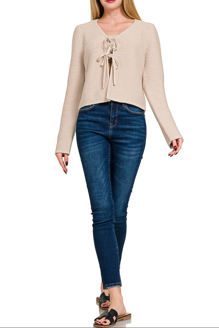 Sand beige cropped tie-front cotton sweater cardigan with long sleeves and knit texture. 100% Cotton. 