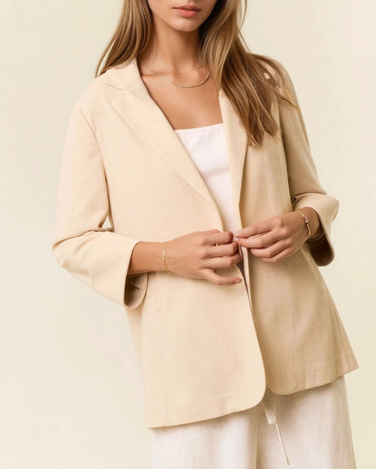 Woman wearing a beige blazer over a white top on a light background.