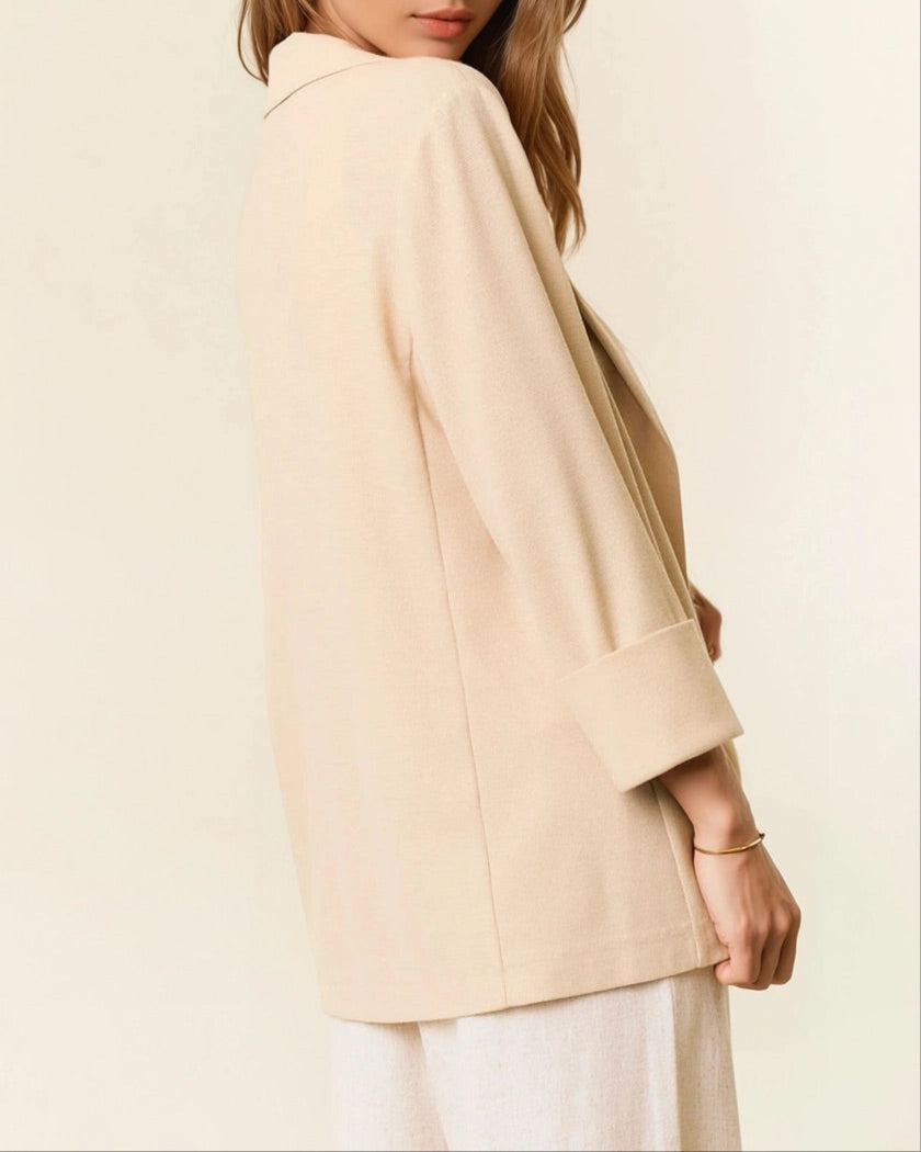 Woman wearing a beige blazer jacket against a plain background.
