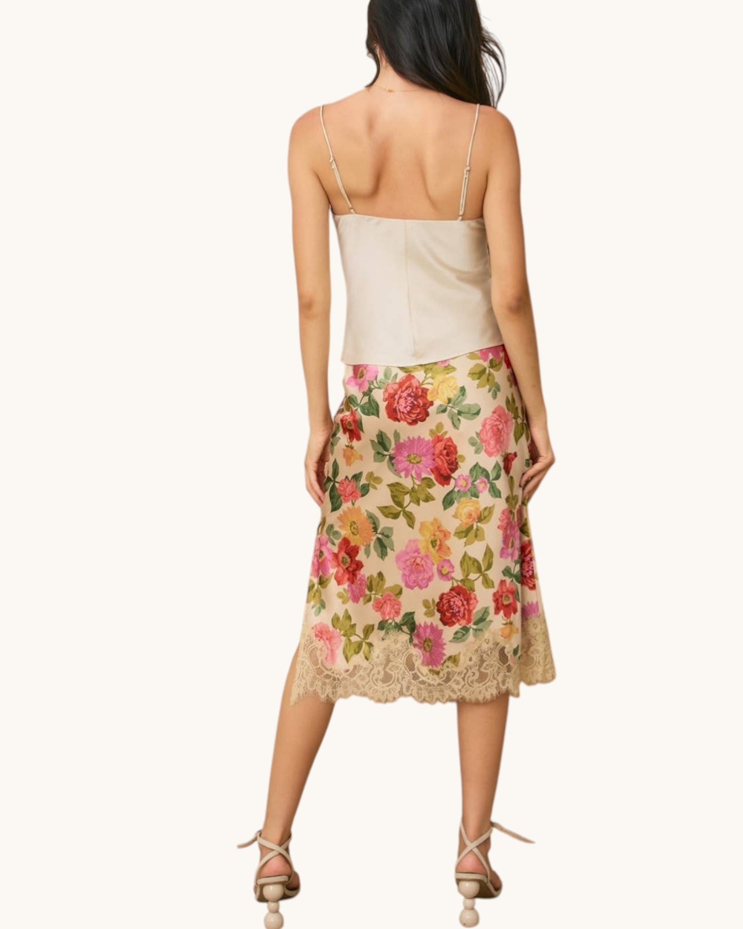 Woman wearing a floral skirt with a plain background.