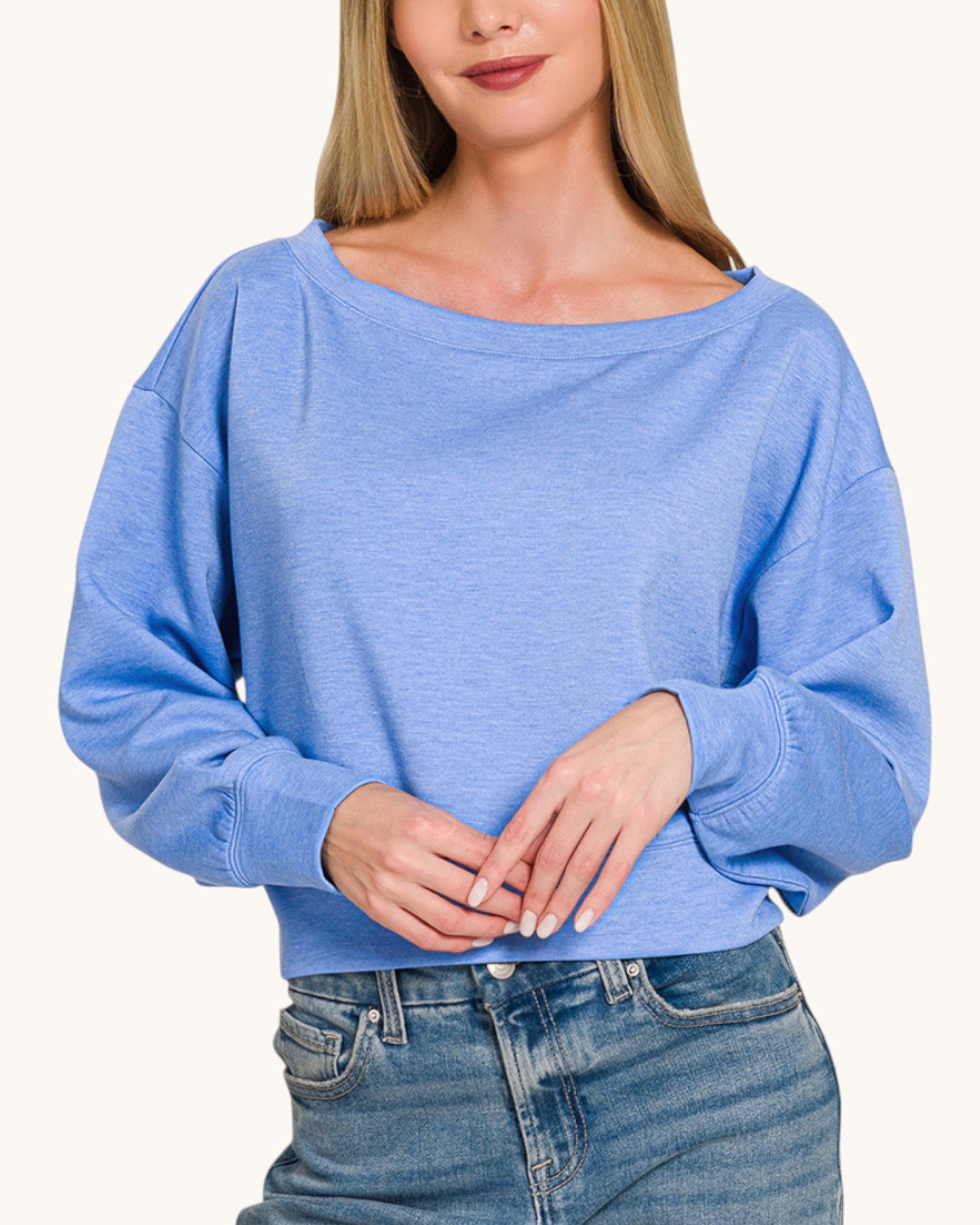 Woman wearing a blue cropped scuba sweatshirt and jeans on a white background.