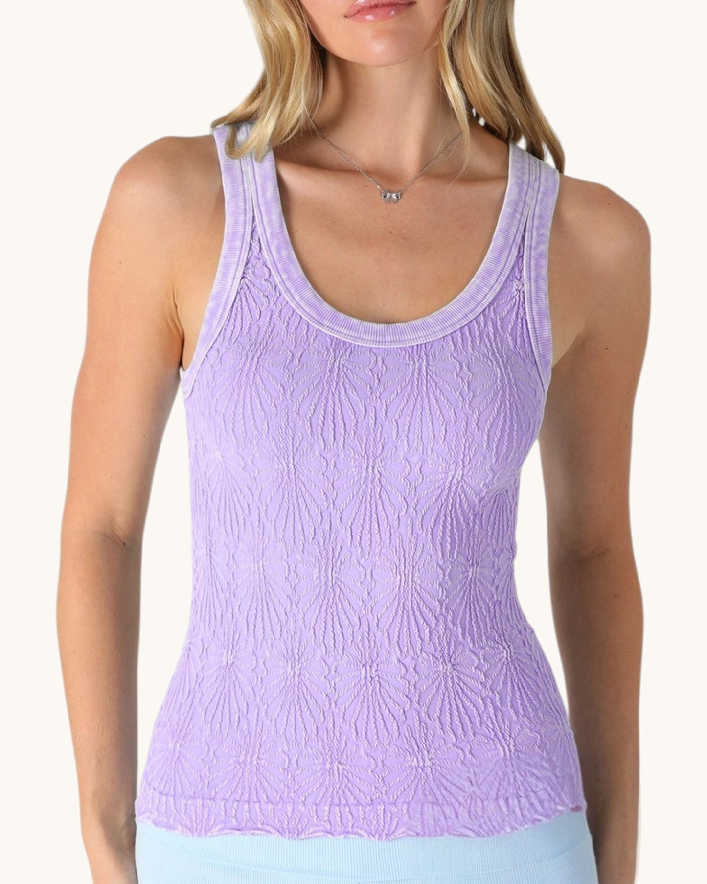 Woman wearing a light purple floral textured tank top on a white background.