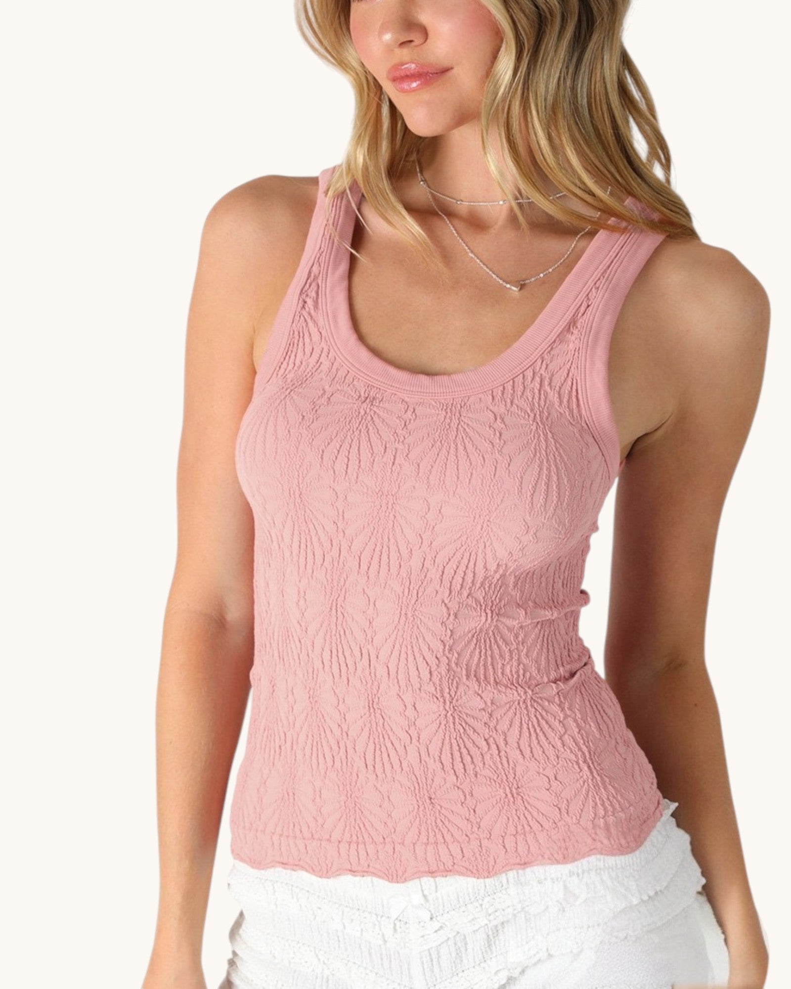 Woman wearing a pink textured tank top on a white background.