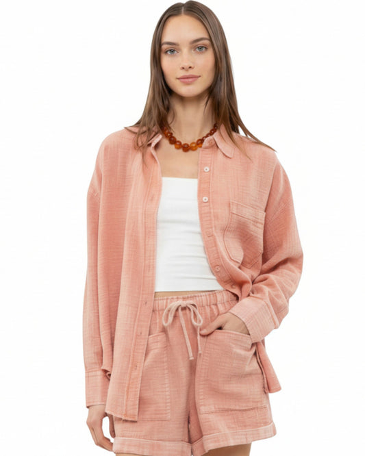 Woman wearing a sienna pink textured button up and matching shorts on a white background.