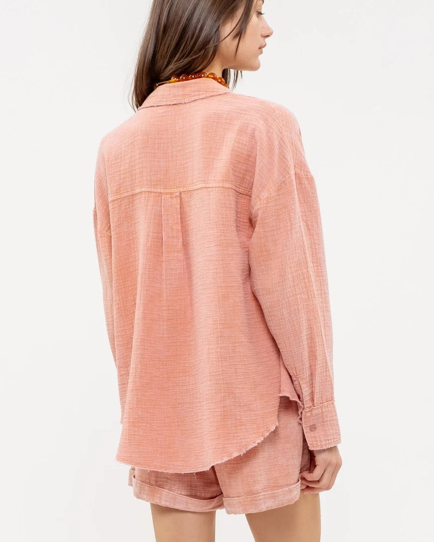 Woman wearing a sienna pink textured button up and matching shorts on a white background.