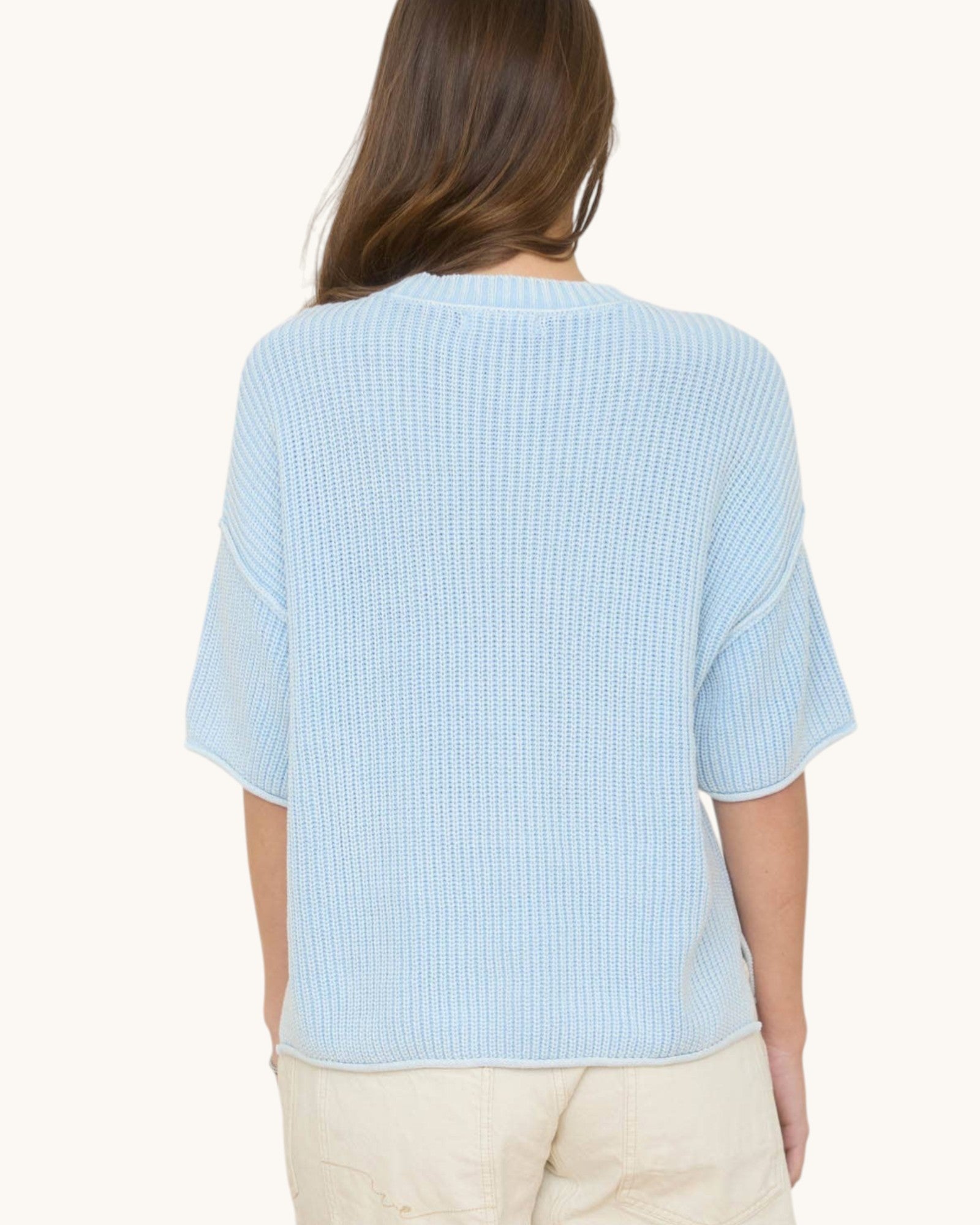 Light blue textured top worn by a person on a white background.