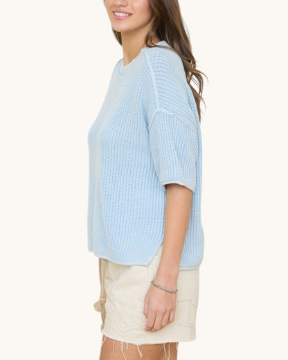 Woman wearing a light blue ribbed sweater on a white background