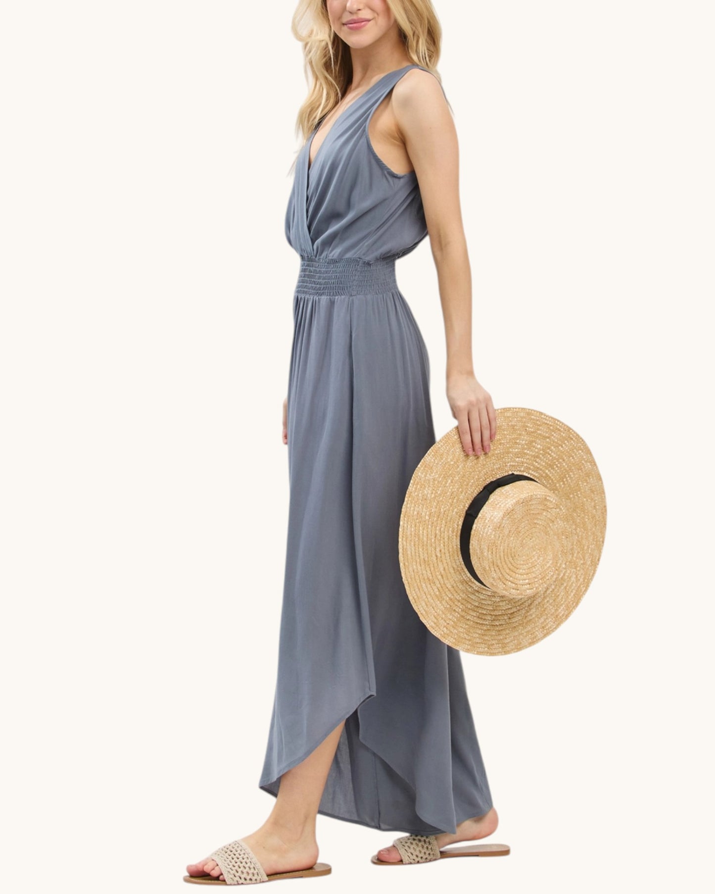Side view of a woman wearing a slate blue jumpsuit on a white background.