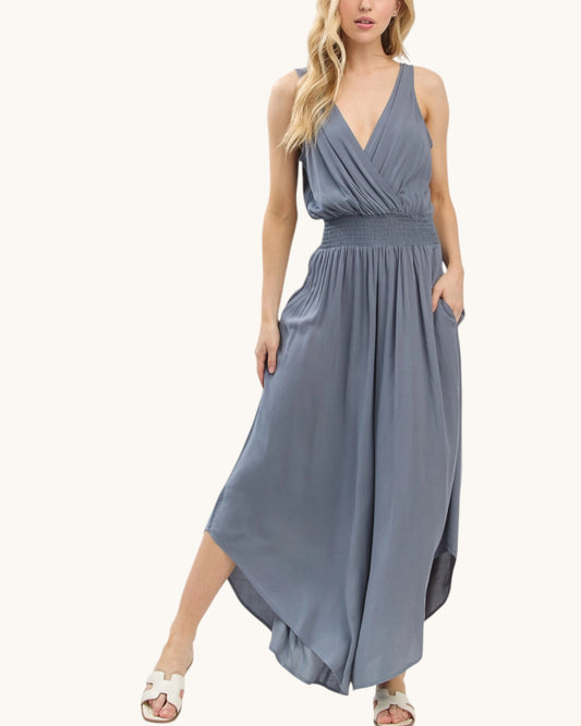 Woman wearing a slate blue jumpsuit on a white background.
