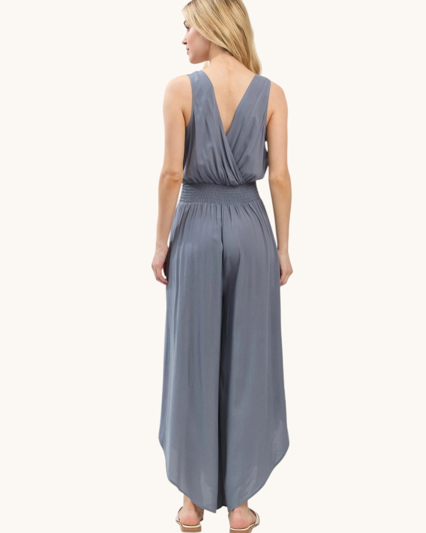 Woman wearing a slate blue jumpsuit on a white background.