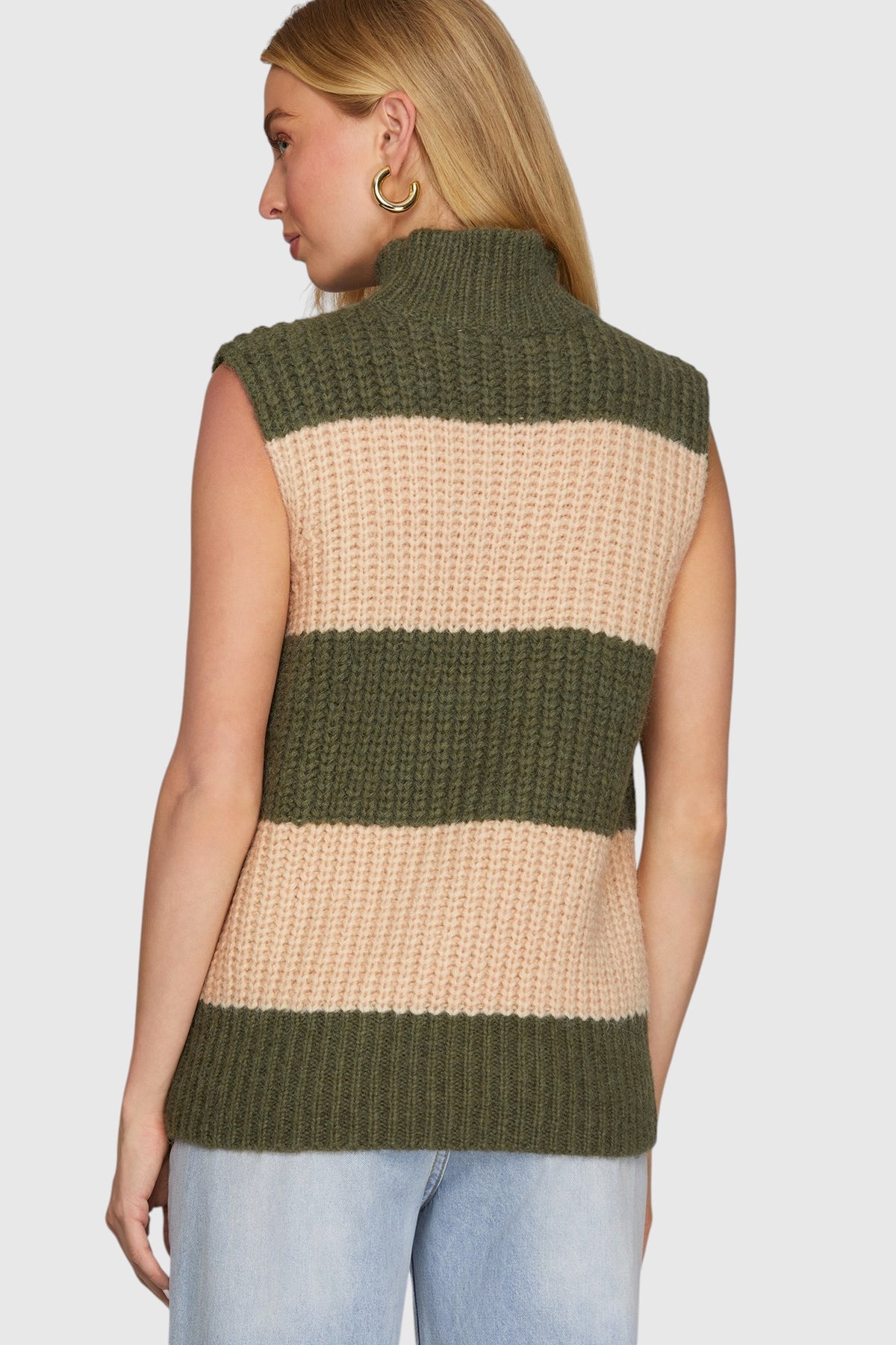 A woman shown from the back wearing a sleeveless ribbed knit sleeveless sweater with thick horizontal stripes in olive green and beige, paired with light blue jeans against a light gray studio background.