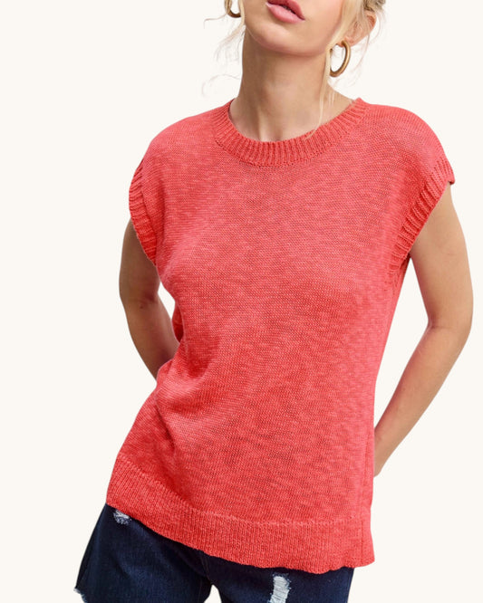 Person wearing a coral sleeveless sweater on a white background.