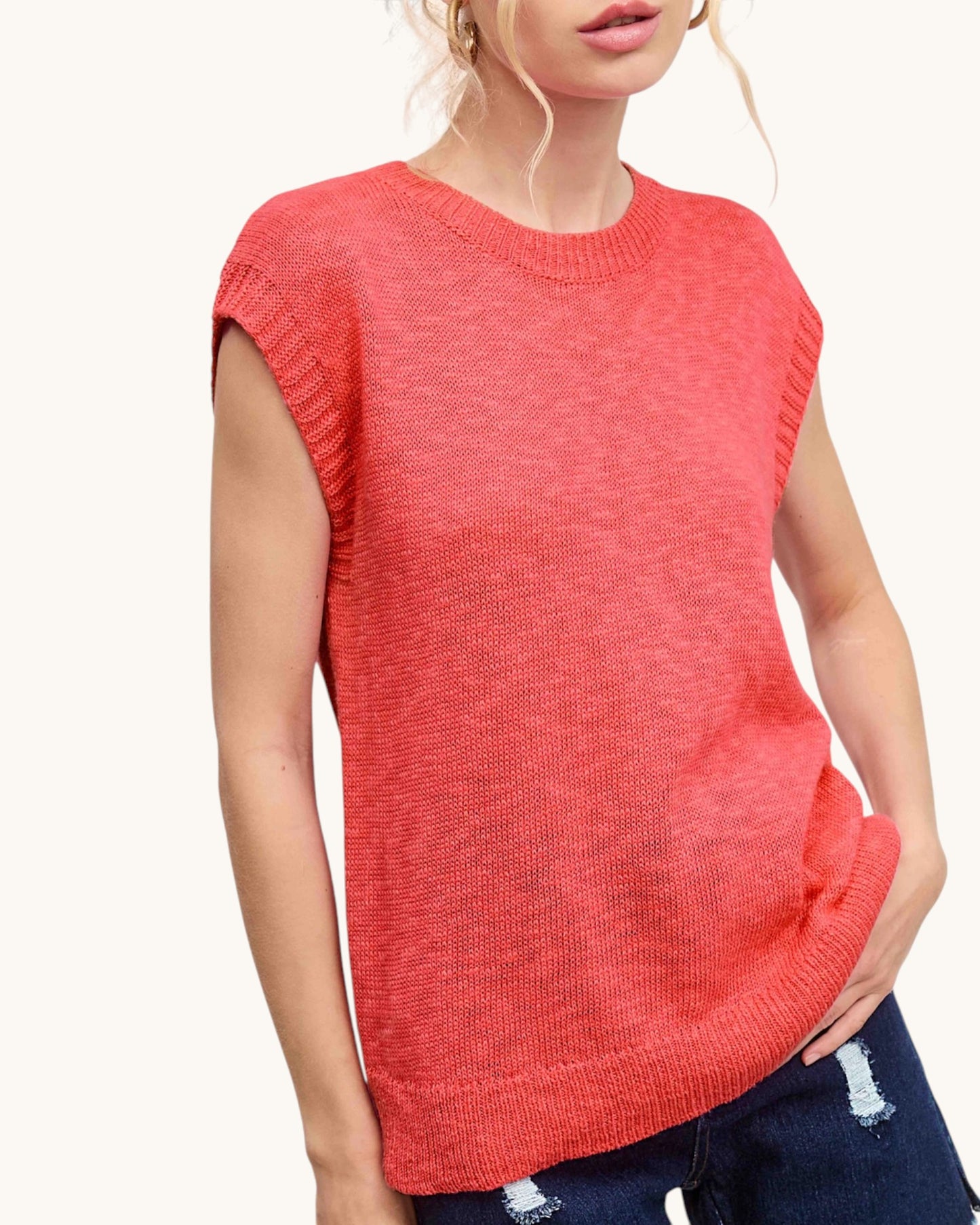 Person wearing a red sleeveless sweater on a white background.