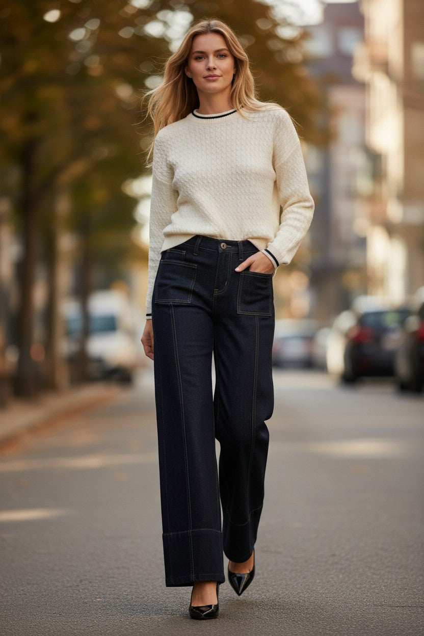 Woman wearing a white sweater and Dark Wash Mid Rise Wide Hem Trouser Jeans with stovepipe leg with city background.