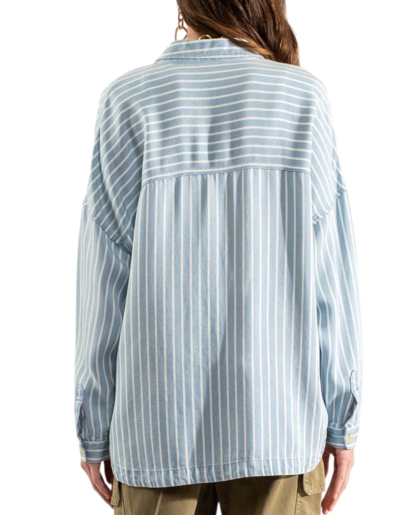 Woman wearing a blue and white striped shirt with olive cargo pants on a white background.