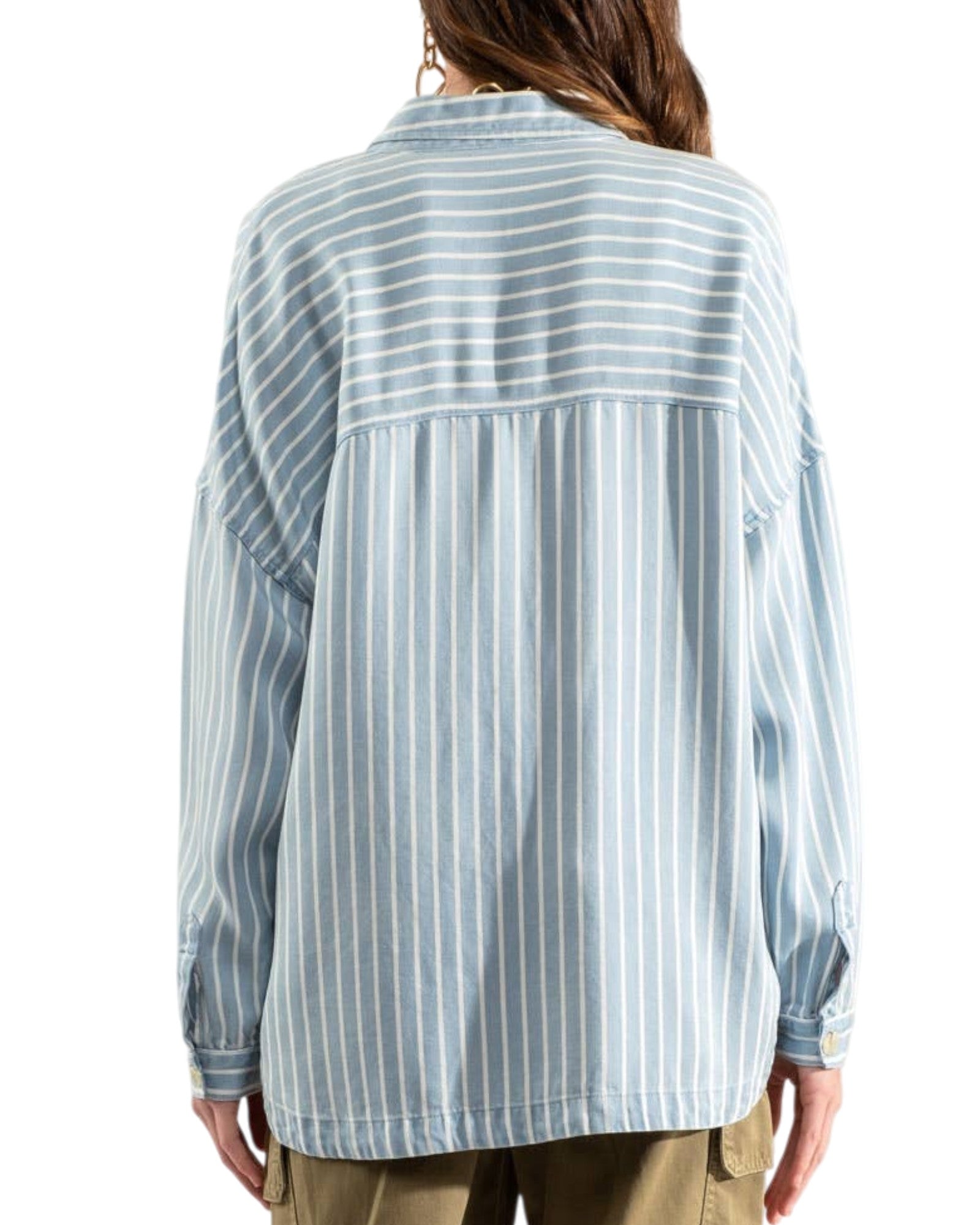 Woman wearing a blue and white striped shirt with olive cargo pants on a white background.