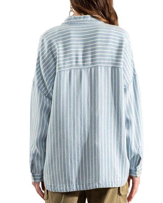 Woman wearing a blue and white striped shirt with olive cargo pants on a white background.