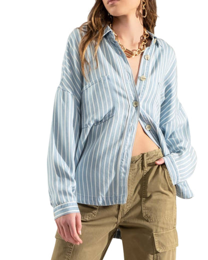 Woman wearing a blue and white striped shirt with olive cargo pants on a white background.