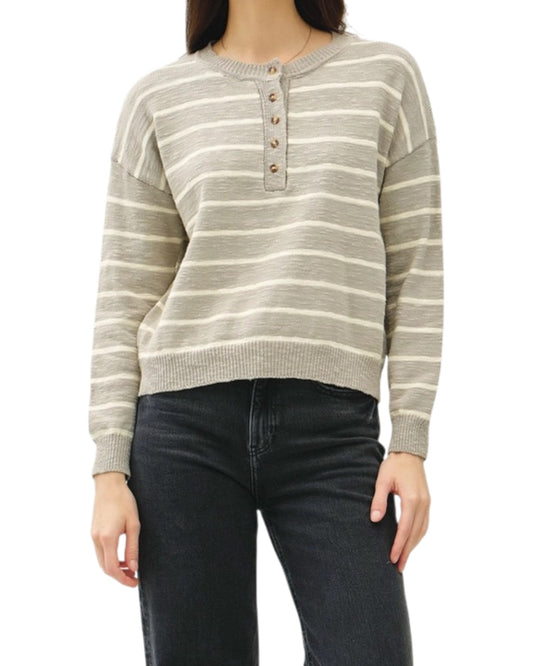 Person wearing a striped sweater and dark jeans on a white background.