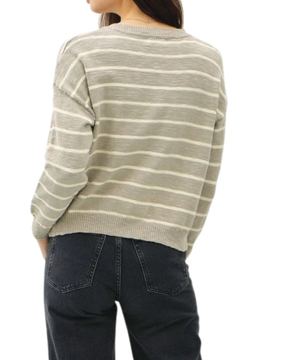 Person wearing a striped sweater and dark jeans on a white background.