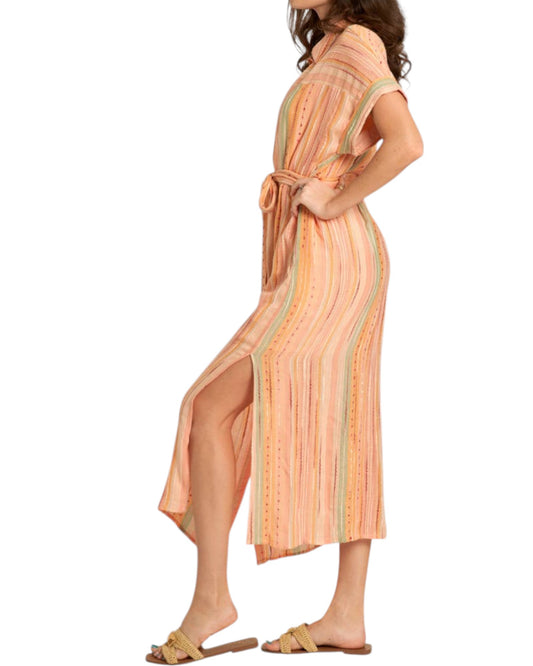 Woman wearing a peach-colored striped midi dress with a slit on a white background.