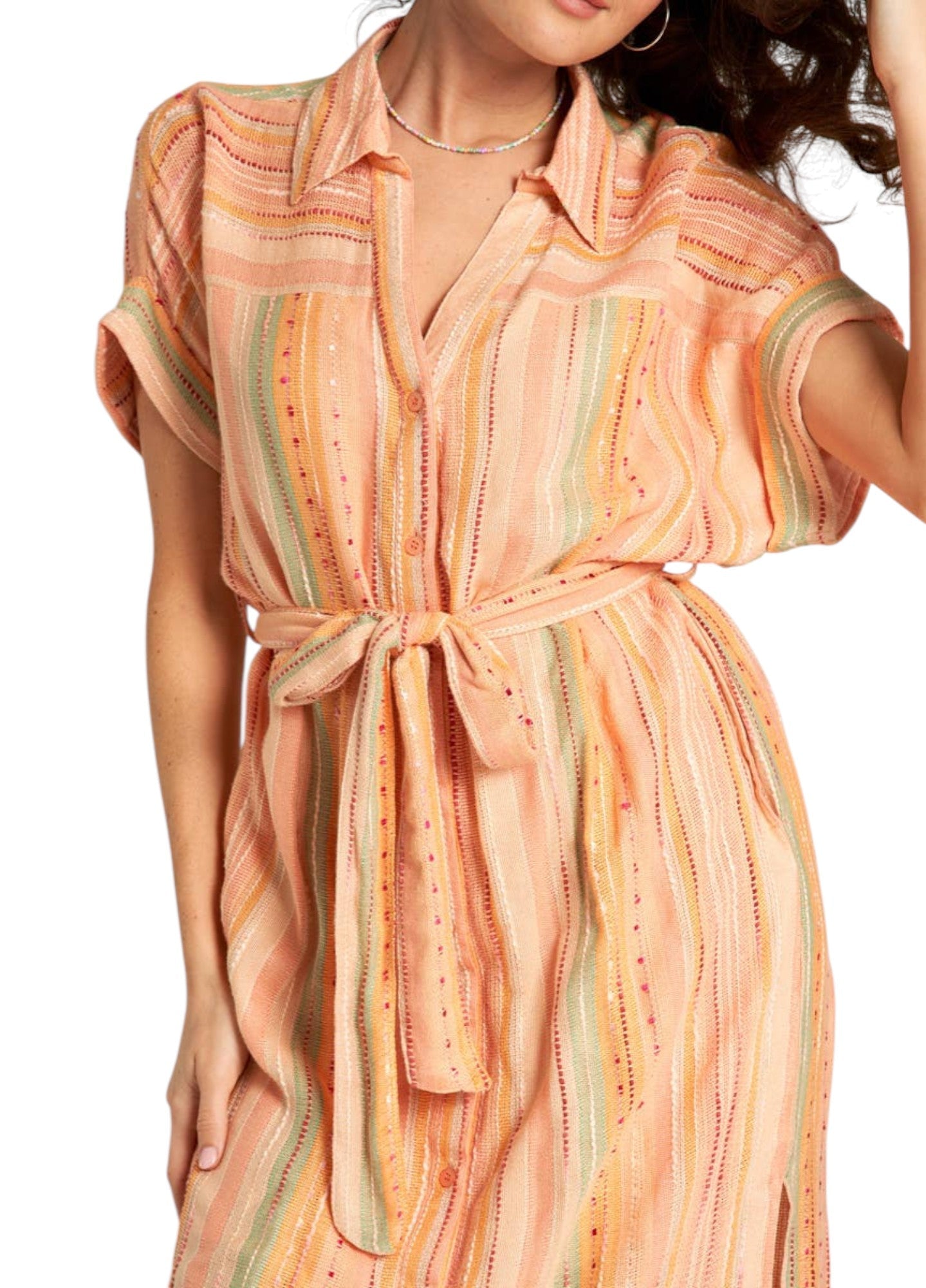 Woman wearing a peach-colored striped midi dress with a slit on a white background.