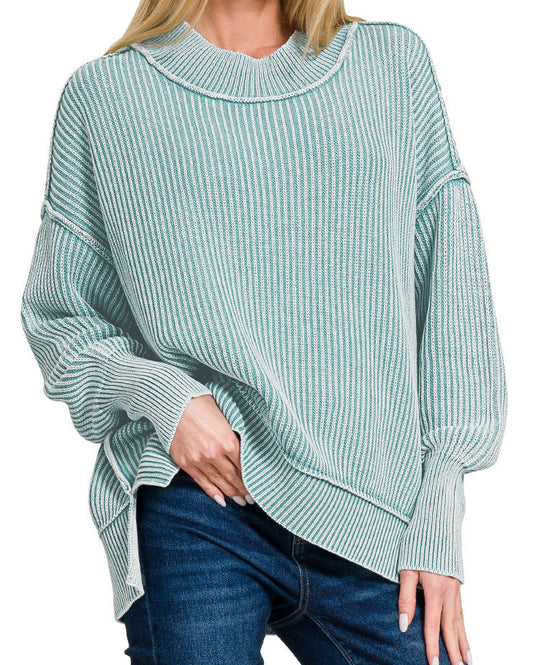 Woman wearing a dusty teal sweater with a white background.