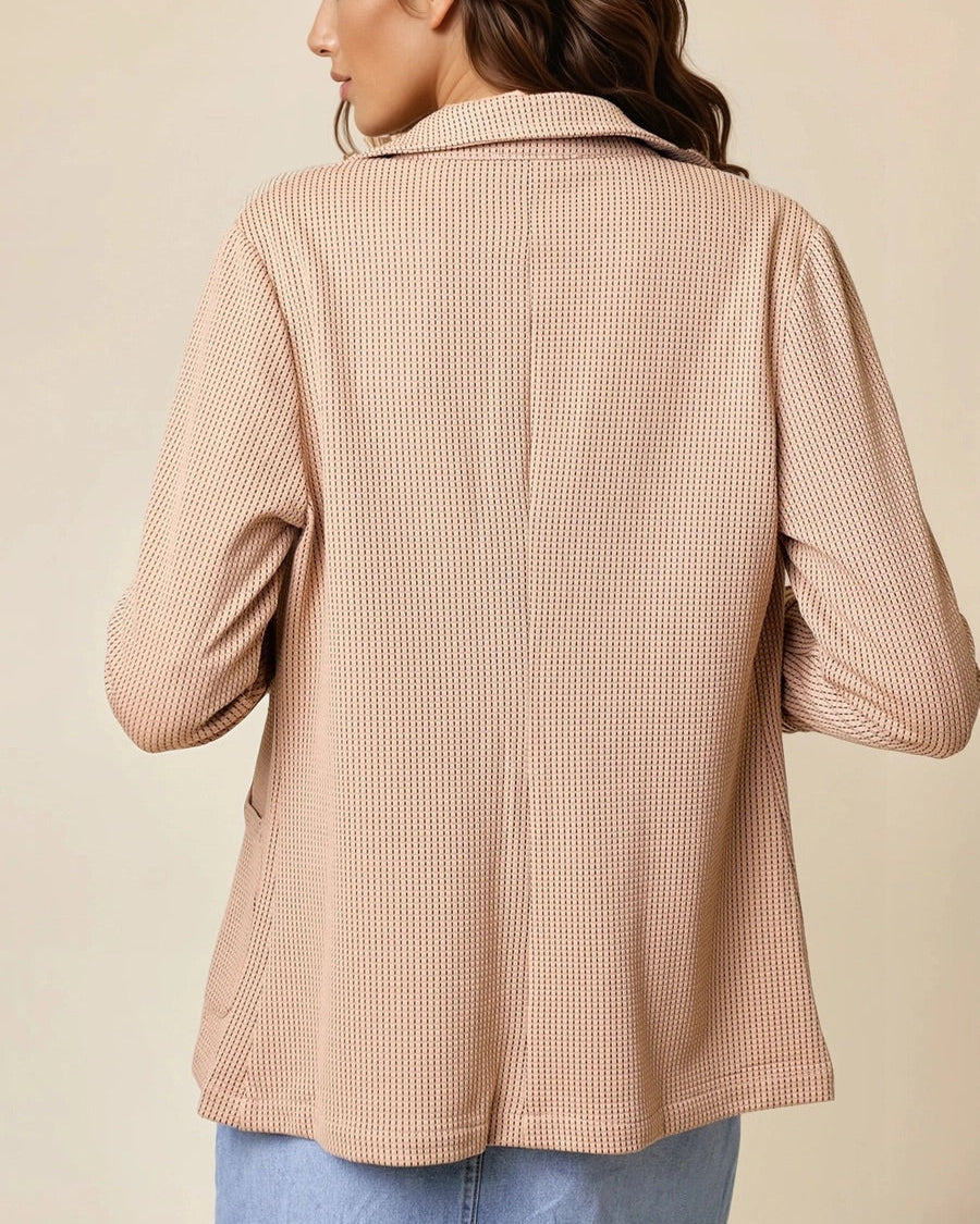 Woman wearing a tan jacket against a beige background. 