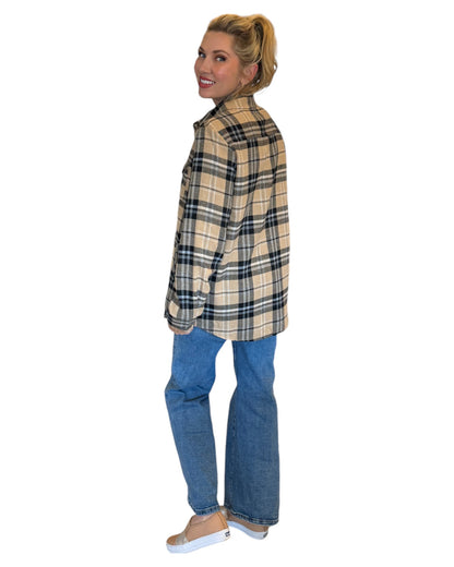 Woman wearing a tan and black plaid flannel and blue jeans.