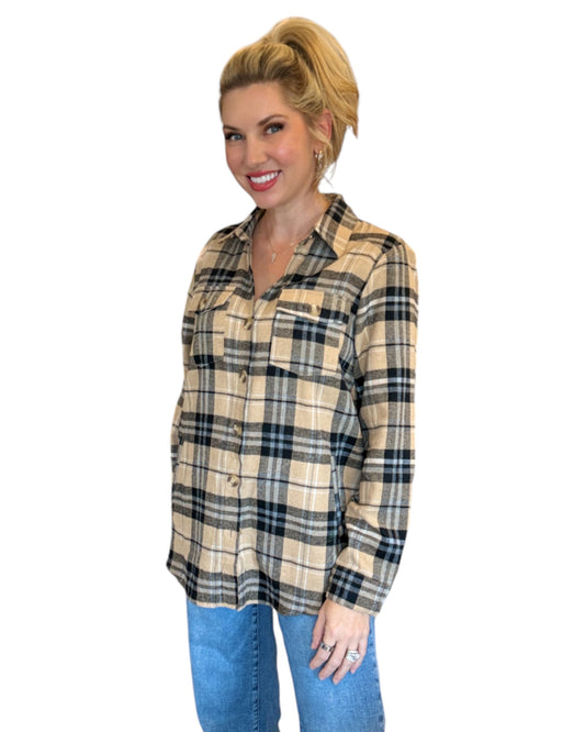 Woman wearing a tan and black plaid flannel and blue jeans.