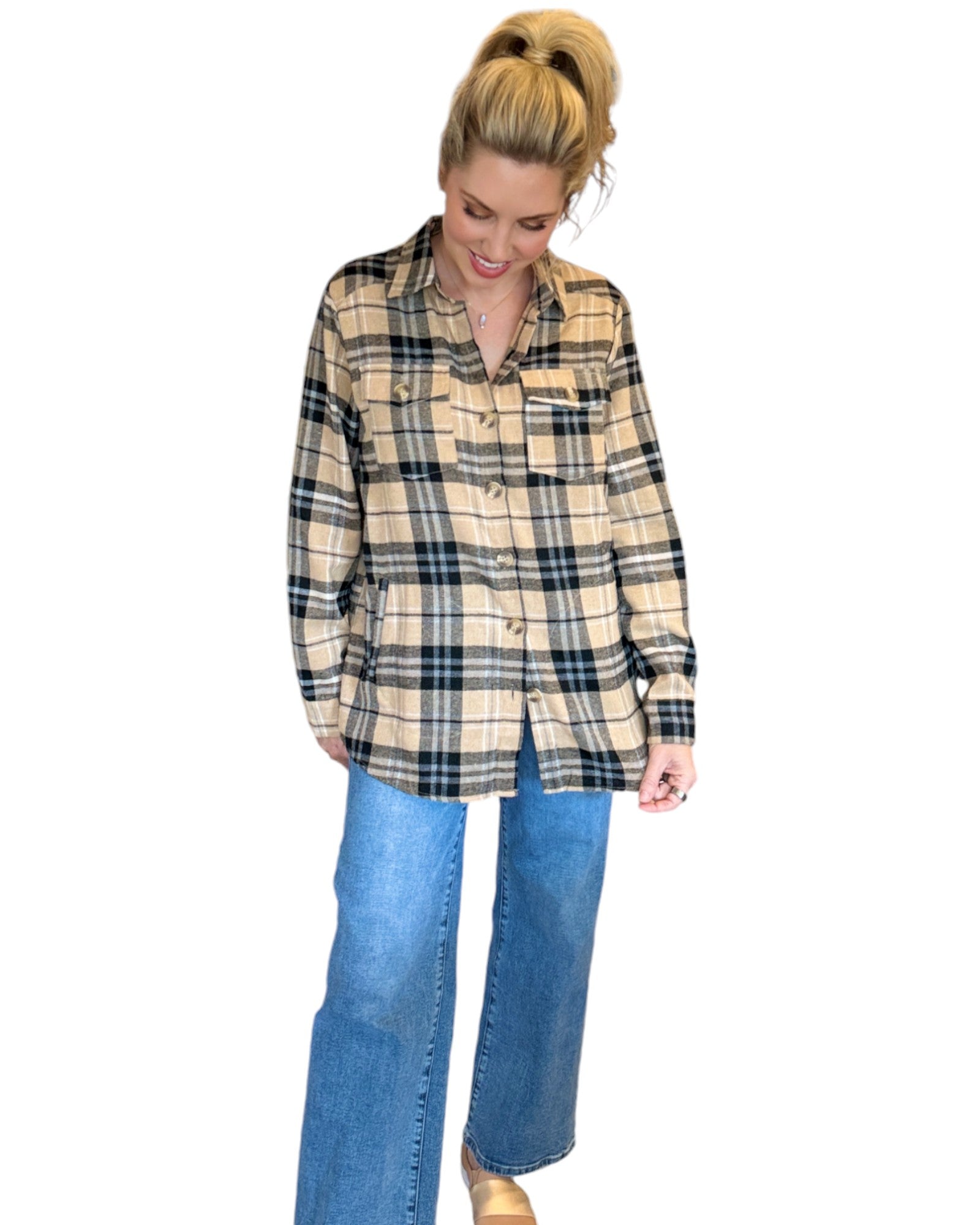 Woman wearing a tan and black plaid flannel and blue jeans.