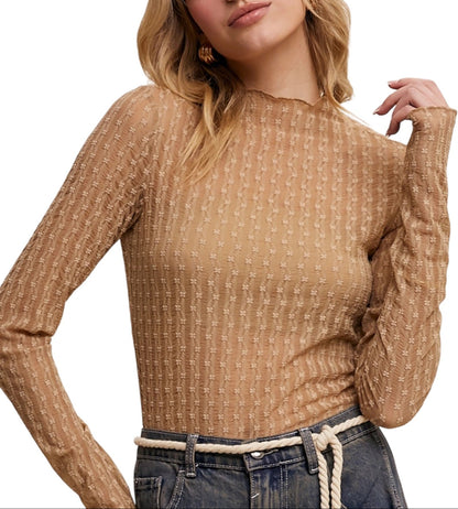 Woman wearing a tan textured sweater with a plain background.