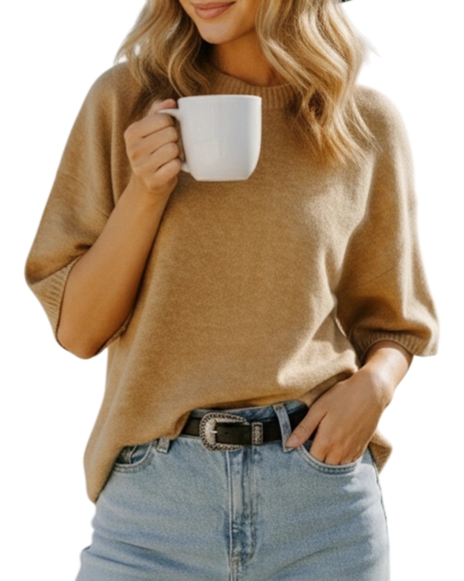 Person wearing a tan sweater and blue jeans, holding a white mug.