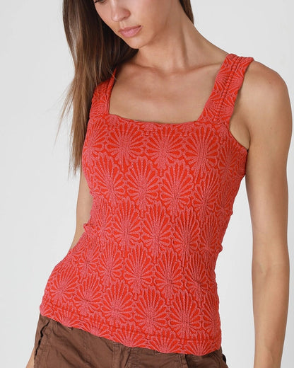 Woman wearing a red  floral patterned tank top on a white background.