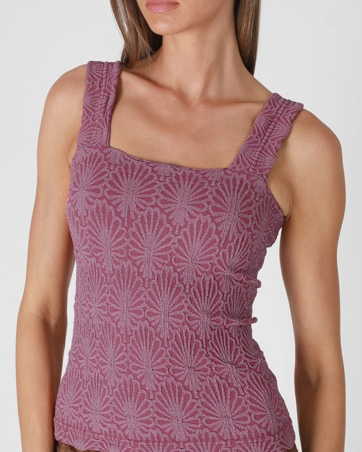 Woman wearing a purple patterned top on a white background.