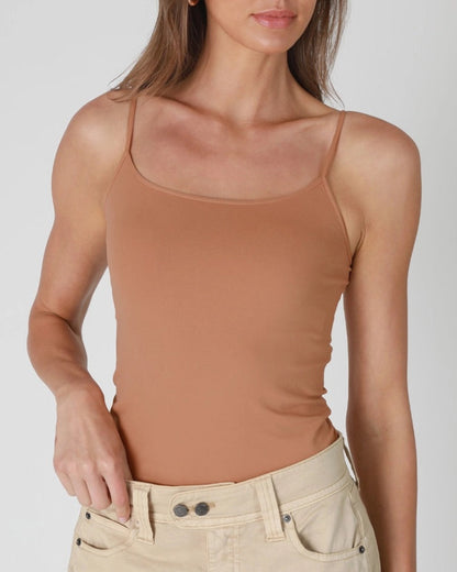 Woman wearing a tan tank top and beige pants on a white background.