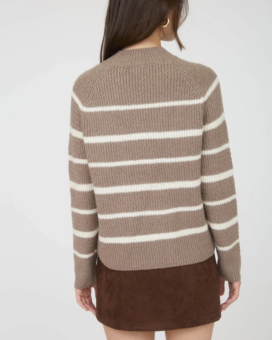 Woman wearing a taupe and ivory striped mock neck sweater with a brown skirt on a white background.