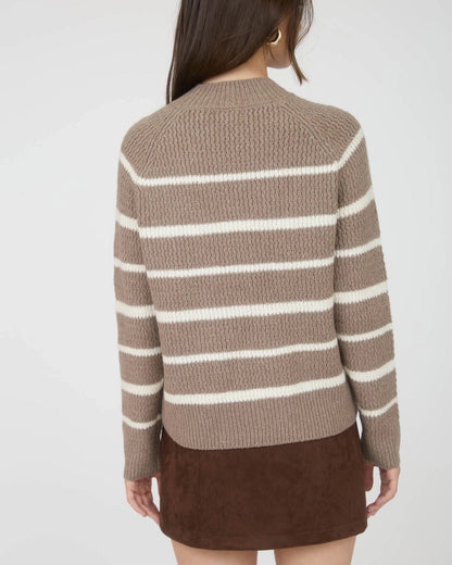 Woman wearing a taupe and ivory striped mock neck sweater with a brown skirt on a white background.