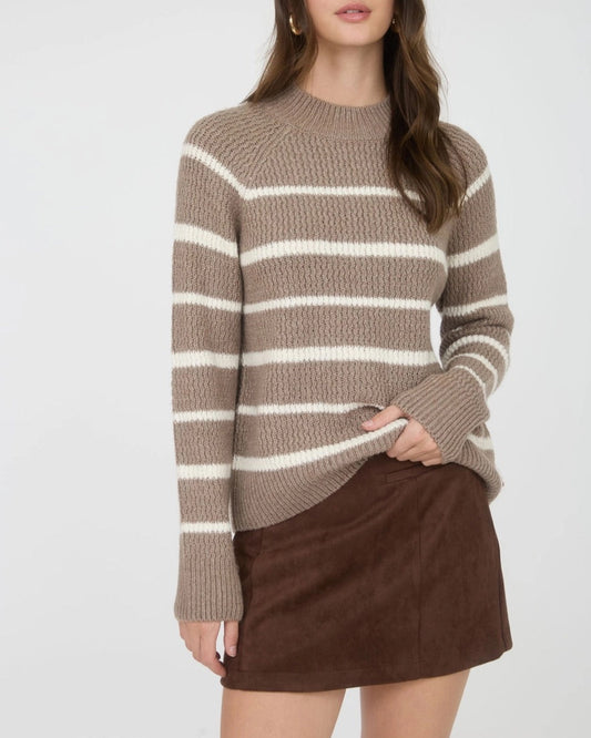 Woman wearing a taupe and ivory striped mock neck sweater with a brown skirt on a white background.
