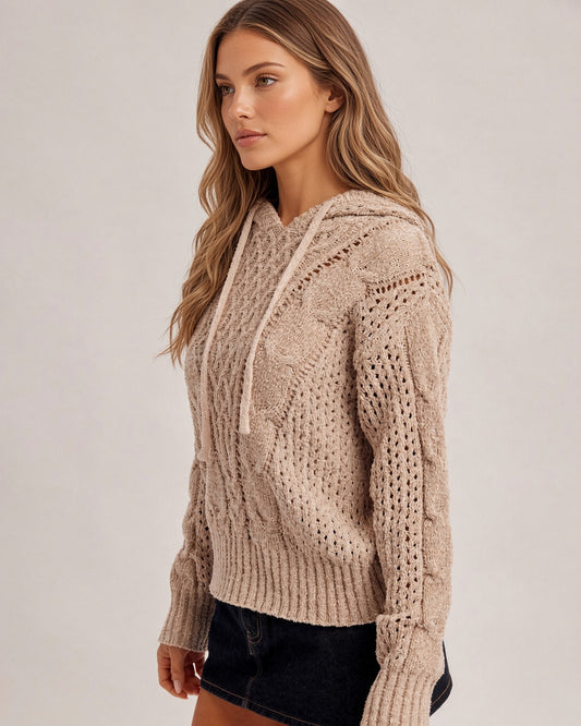 Side profile of a woman wearing a speckled taupe pointelle stretchy hoodie sweater and black denim skirt.