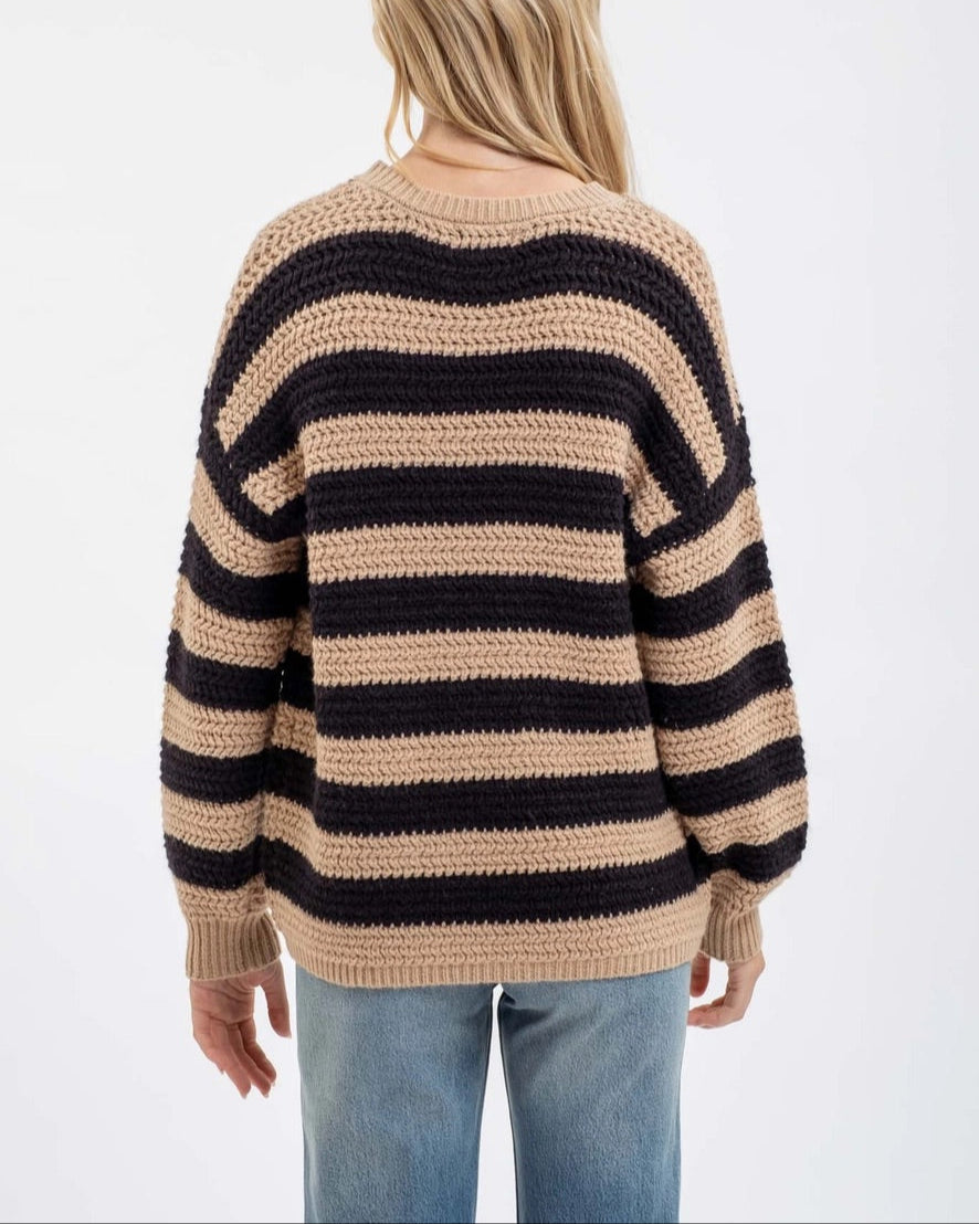 Person wearing a striped sweater with beige and black horizontal stripes on a white background.