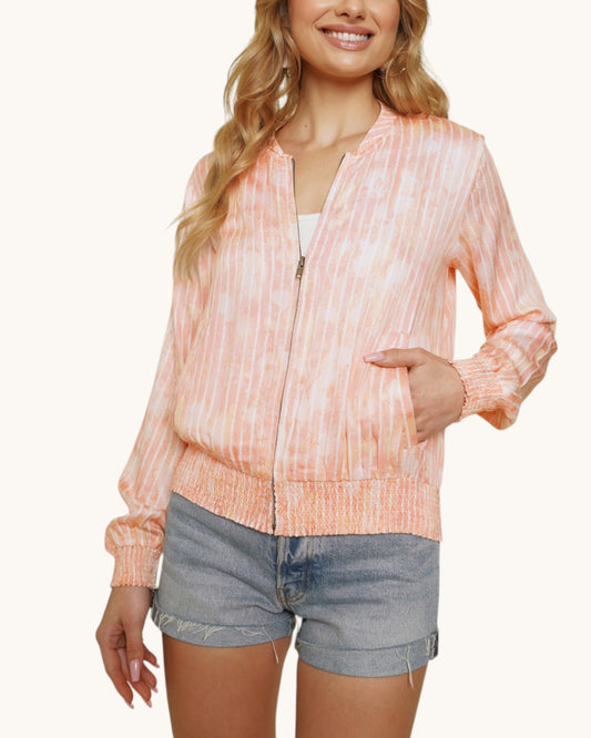 Person wearing a pinky-coral washed bomber jacket and denim shorts on a white background.