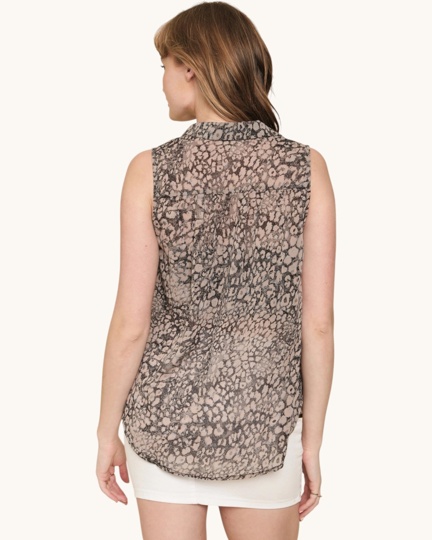 Woman wearing a sleeveless patterned top on a white background.