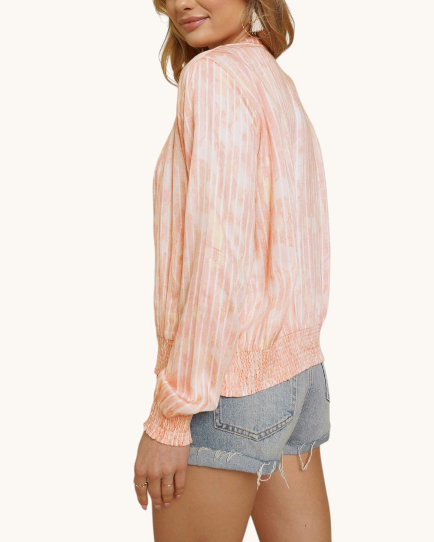 Person wearing a pinky-coral washed bomber jacket and denim shorts on a white background.