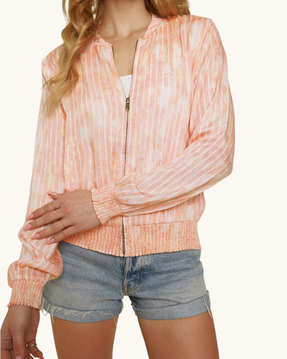Person wearing a pinky-coral washed bomber jacket and denim shorts on a white background.