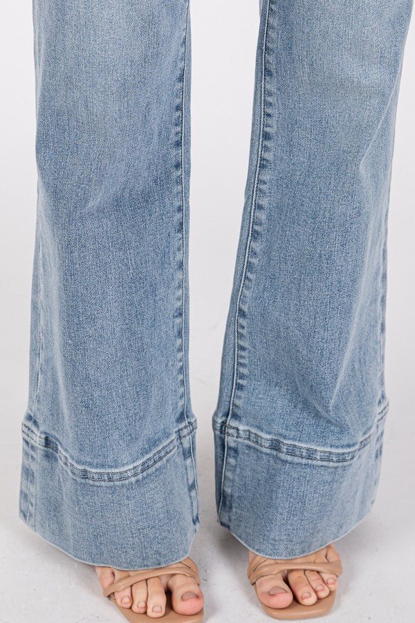 Close-up and full-length views of high-rise wider leg jeans with exaggerated trouser hem in a light/medium wash denim.