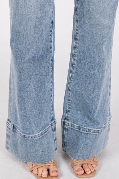 Close-up and full-length views of high-rise wider leg jeans with exaggerated trouser hem in a light/medium wash denim.