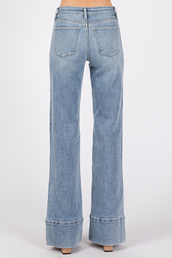 Close-up and full-length views of high-rise wider leg jeans with exaggerated trouser hem in a light/medium wash denim.